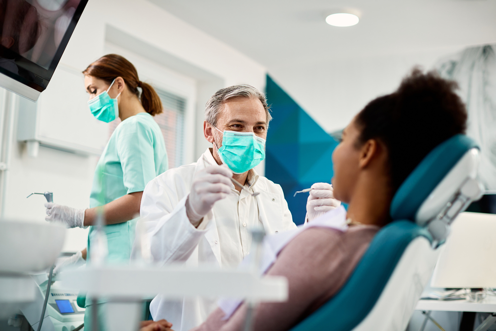 Smiling,Dentist,Communicating,With,African,American,Woman,While,Checking,Her